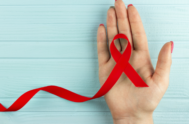Rote Schleife als Symbol für HIV auf Handfläche