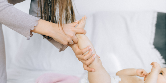 Frau massiert Fuß eines Babys